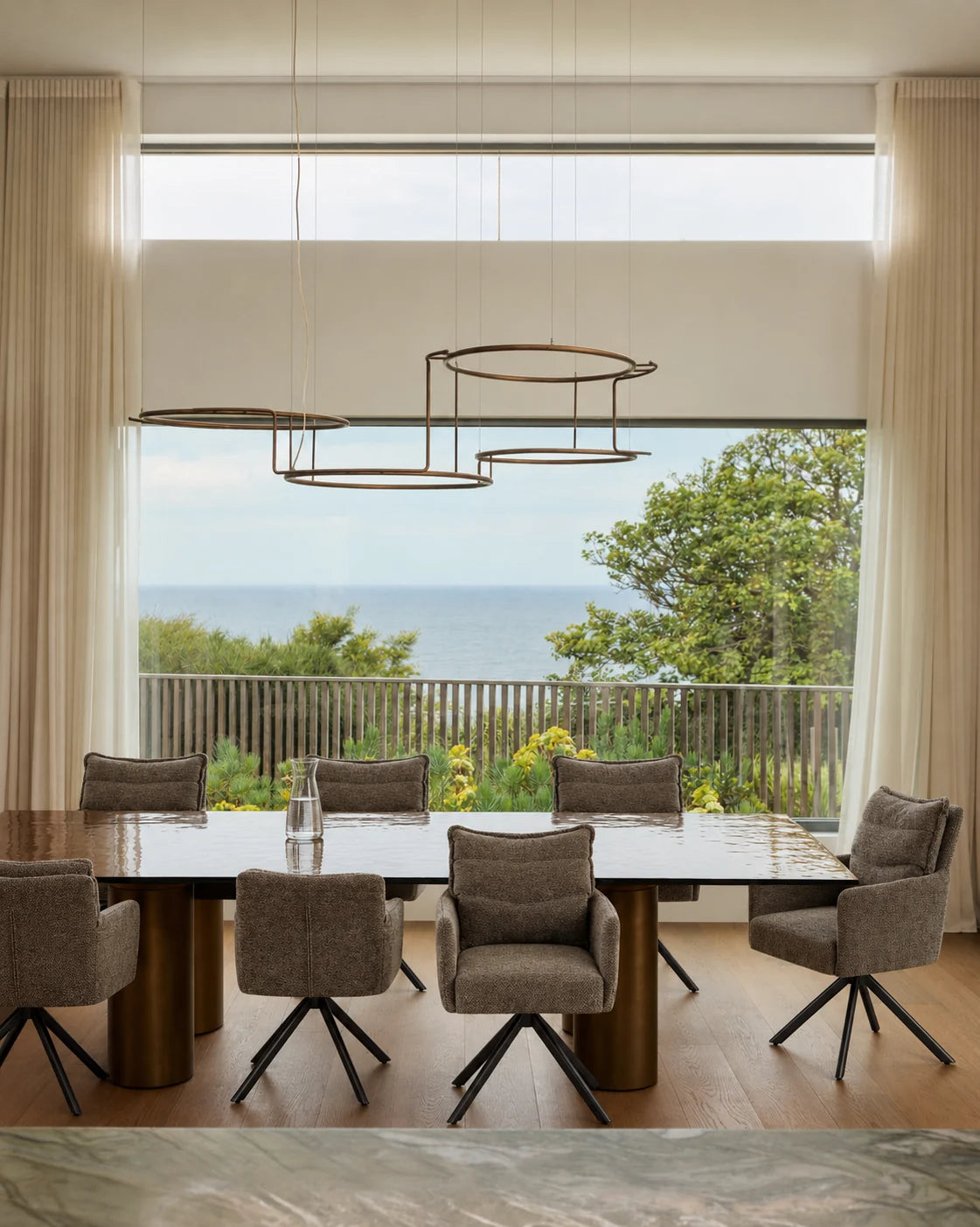 Chaises pivotantes autour d'une grande table, vue sur la mer