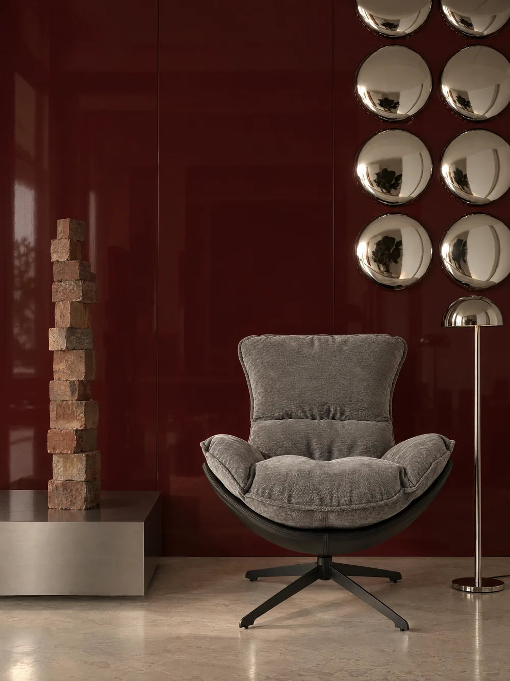 Fauteuil gris devant un mur bordeaux